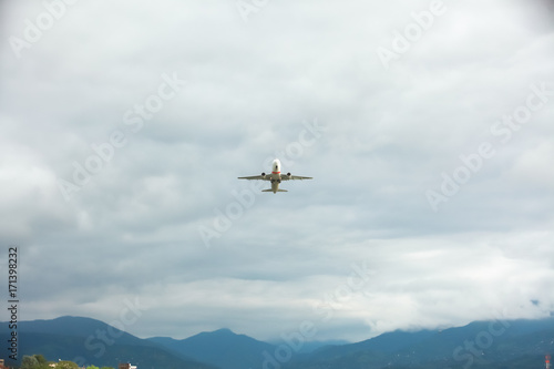 a passenger plane flies into the sky amid the mountains