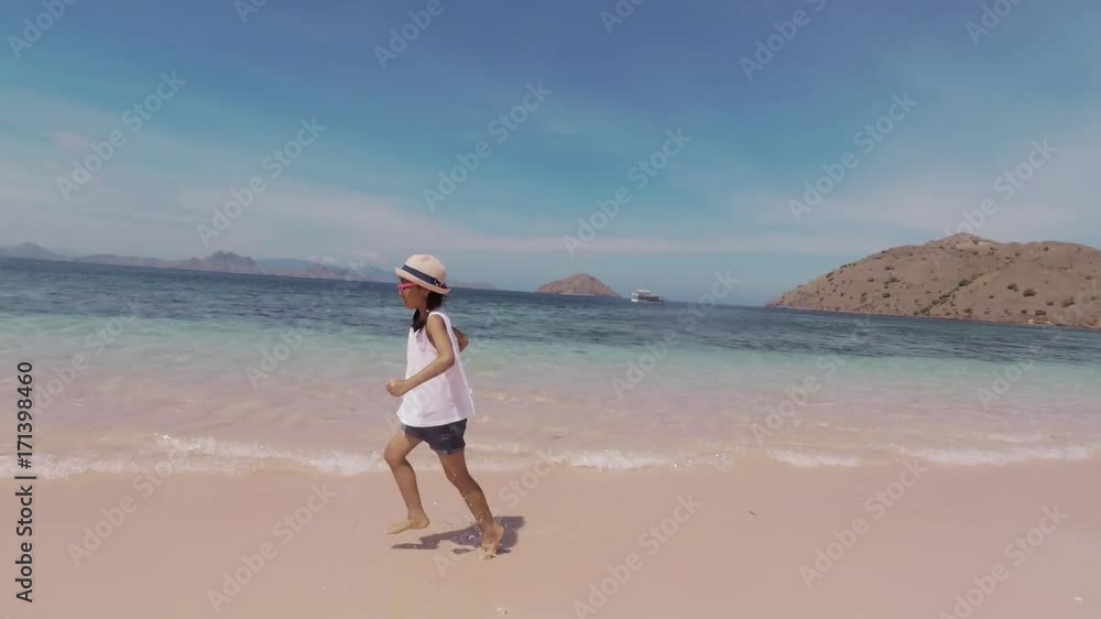 Happy little girl enjoying holiday by running on the Pink Beach at Komodo Island close to Bali, Indonesia Happy little girl enjoying holiday by running on the Pink Beach at Komodo Island close to Bali, Indonesia