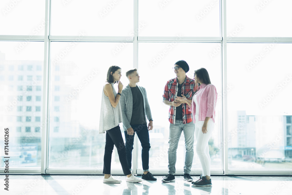 Successful friendly students team are discussing new project in front of panoramic windows Successful friendly students team are discussing new project in front of panoramic windows