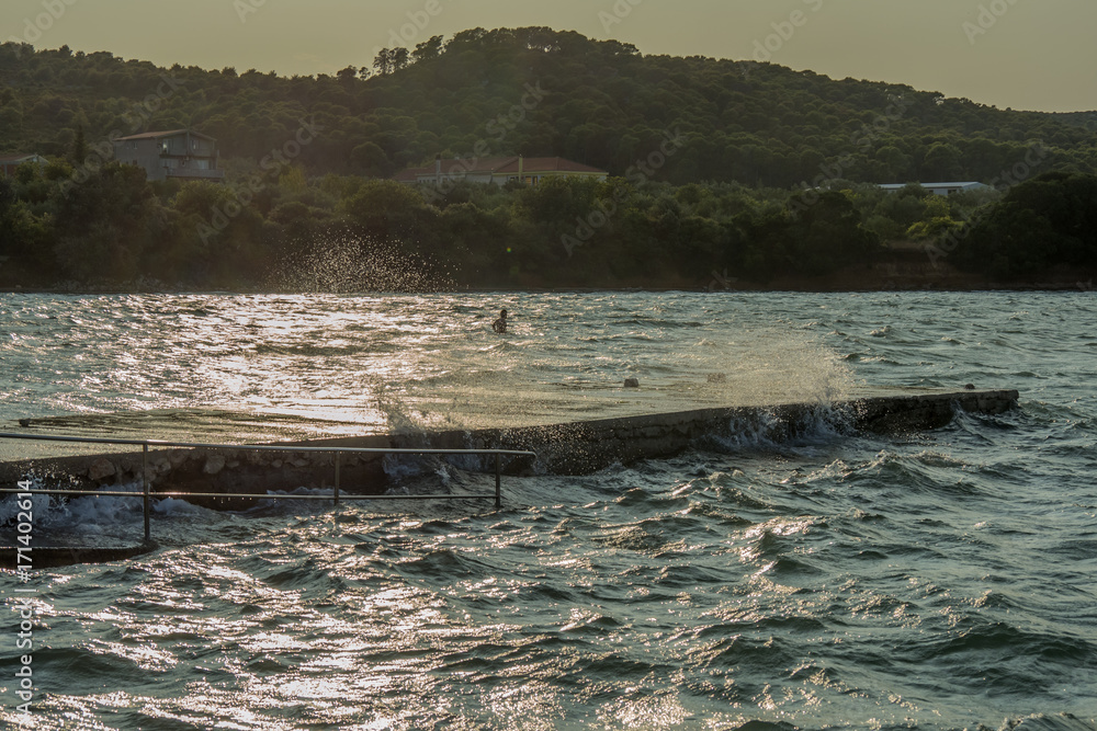 waves hitting pier splashing in sunset