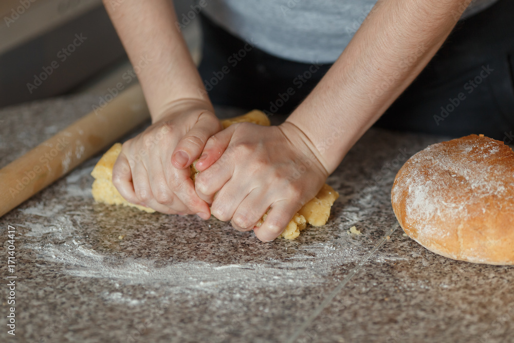 Girl's hands kneading dough in flour on table Girl's hands kneading dough in flour on table