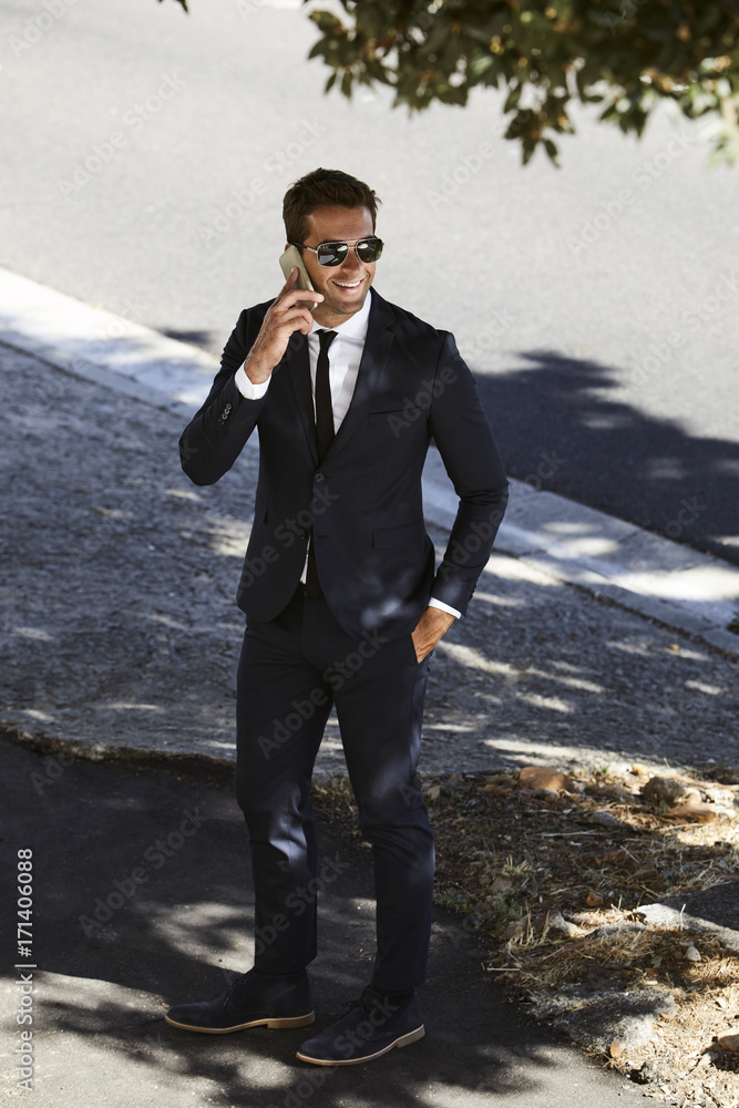 Business dude in shades takes a call on sidewalk Business dude in shades takes a call on sidewalk