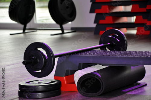 Langhanteltraining: die Sportartikel wie Langhanteln, Gewichtsscheiben und Stepper für Kraft und Ausdauersport in einem Fitnesstudio.