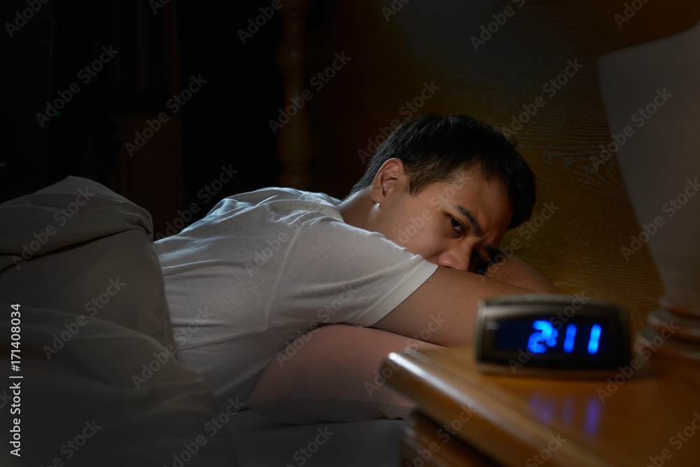Depressed man suffering from insomnia lying in bed Depressed man suffering from insomnia lying in bed