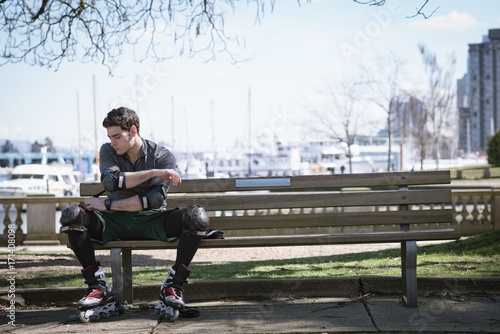 Young man wearing elbow pad while sitting on bench