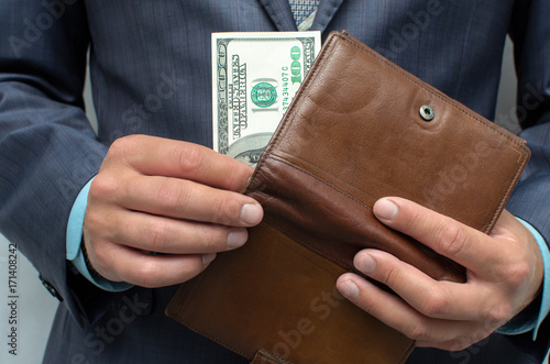 Savings. Poverty. Pay the debts. The man in the suit pulls out one hundred last dollars from wallet.