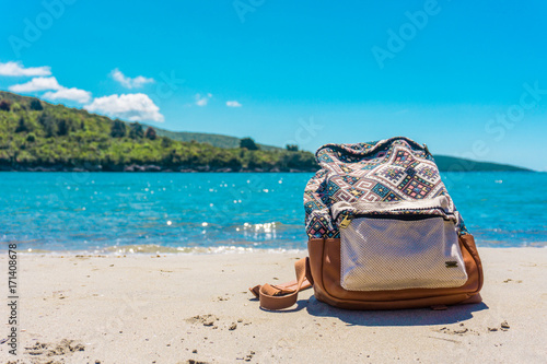 The colourful beautiful travel bag on the amazing background. Landsape like bluesea and white sandin the beach.