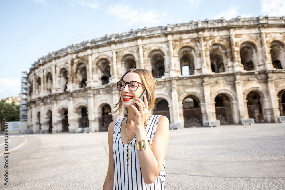 Lifestyle portrait of a young businesswoman walking near old roman amphitheatre in Nimes city, France