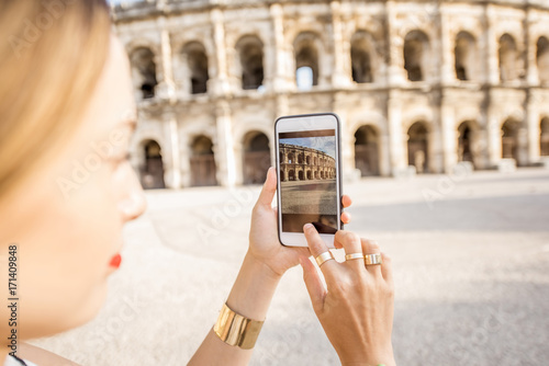 Photography Young woman tourist photographing with smartphone ancient amphitheatre in the ol
