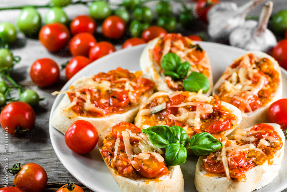 Traditional italian appetizer or bruschetta baked with tomatoes, basil and cheese