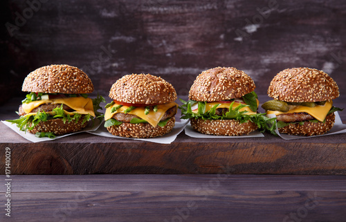 Four homemade hamburgers on wooden table.