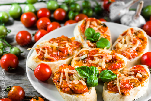 Traditional italian appetizer or bruschetta baked with tomatoes, basil and cheese