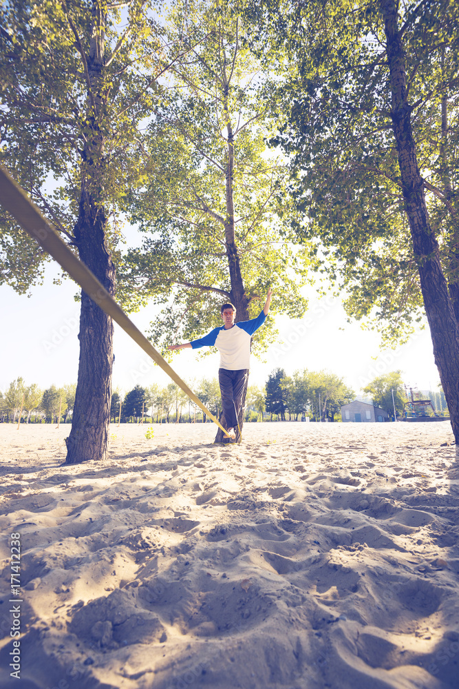 Concentrated man, balancing, begins to walk on slackline Concentrated man, balancing, begins to walk on slackline