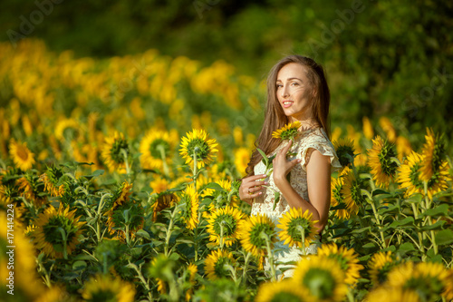 Woman among yellow sunflowers in the field.