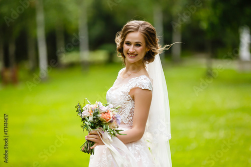 A very beautiful bride in a chic wedding dress. Expensive beautiful accessories. Look down. Portrait of a young girl on wedding day. Photoshoot in a beautiful place and picturesque background