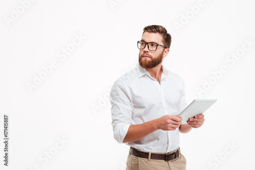Plakat Serious young bearded man using tablet computer.