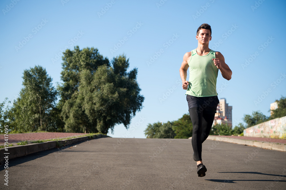 Man running on asphalt road on sunny summer day