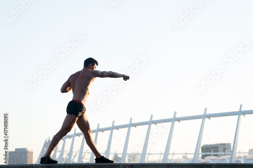 Sportsman with muscular body on white sky
