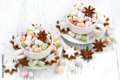 cocoa with colorful marshmallows in cups and Christmas cookies on white background