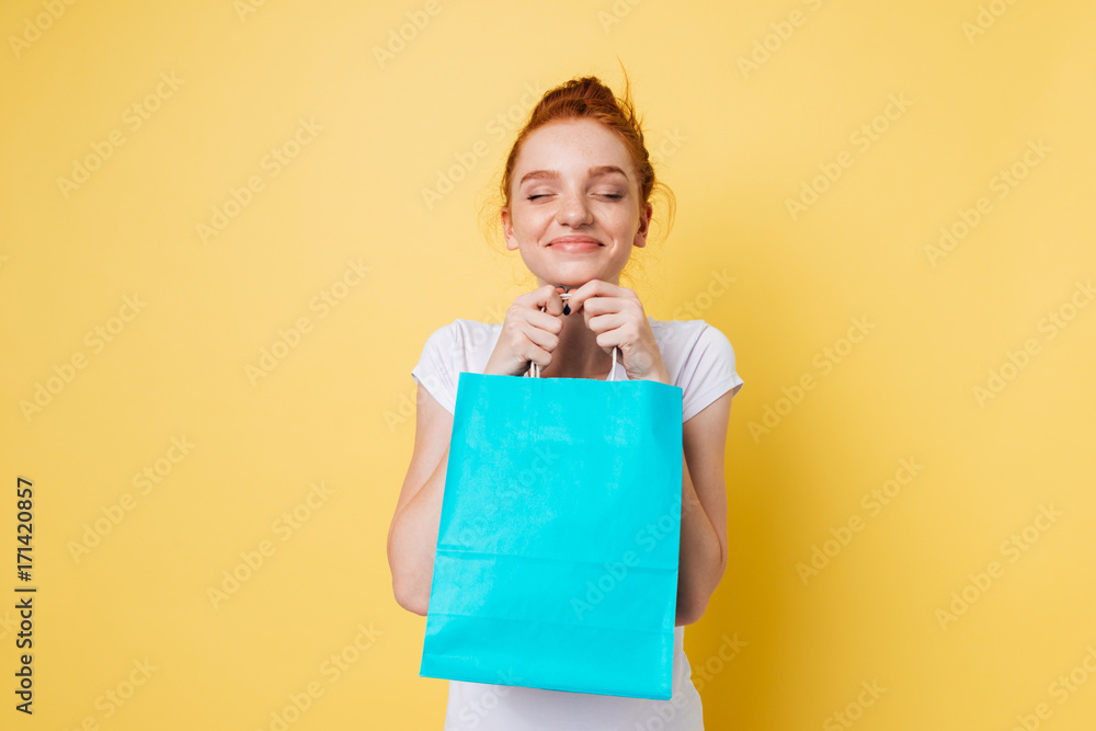 Pleased ginger woman holding packet in hands with closed eyes