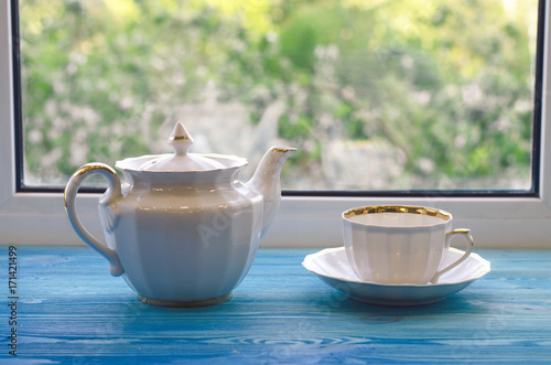 Cup and teapot in front of window.
