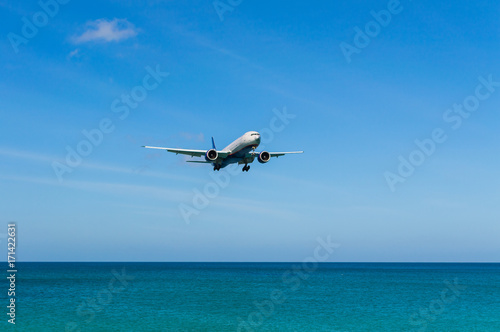 Airplane landing above beautiful beach and sea background © rostovdriver