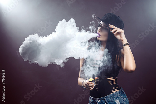 Young sexy woman is vaping. A cloud of vapor. Studio shooting.
