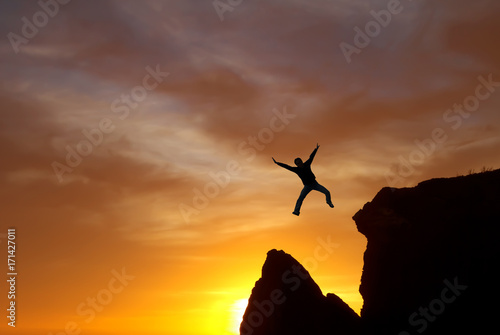 Jumping man against sunset sky background