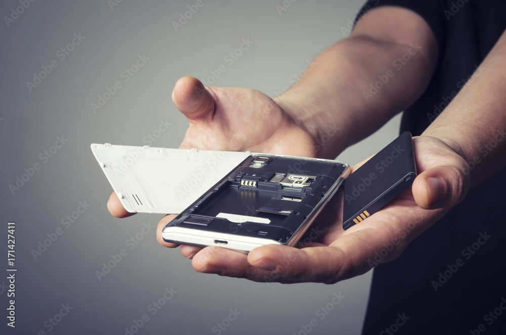 Disassembled phone in repair service. Frustrated man holding a smart phone in hands. Disassembled phone in repair service. Frustrated man holding a smart phone in hands.