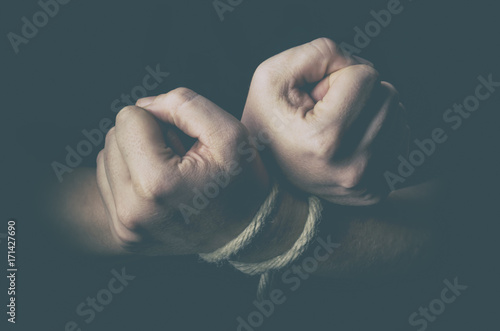 Man with tied hands in low key
