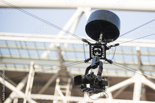 A television camera hangs on cables for football or a concert