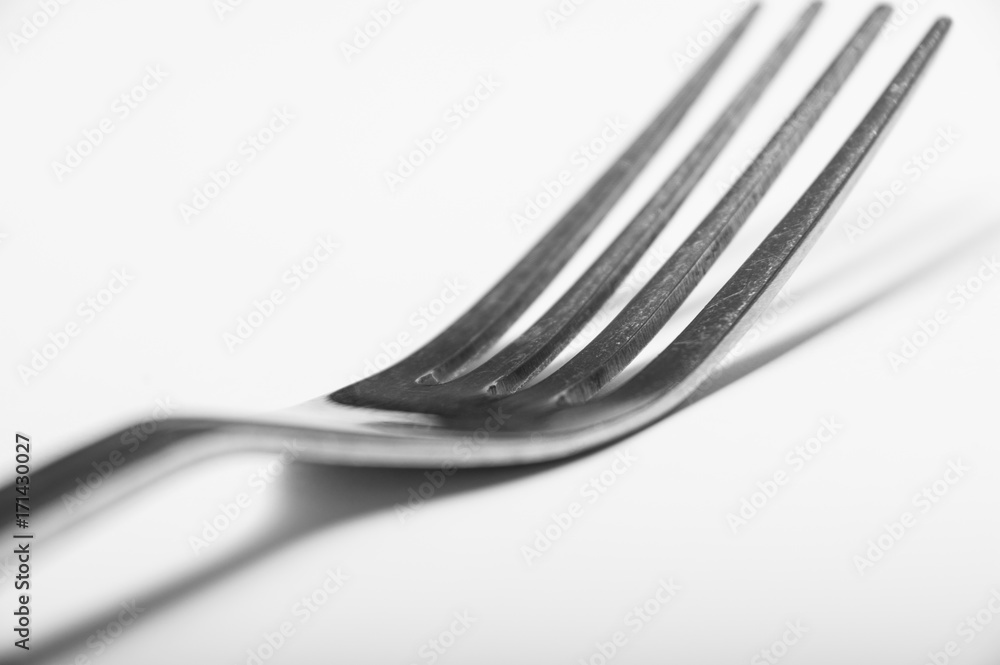 A single silver fork on a white background showing regular wear and tear A single silver fork on a white background showing regular wear and tear