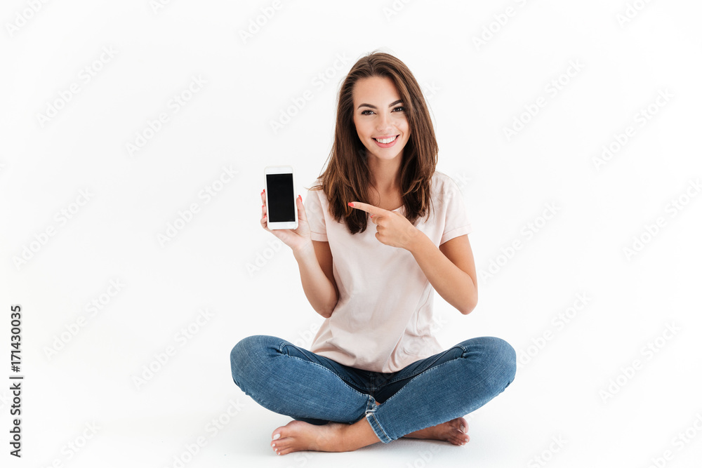 Smiling brunette woman showing blank smartphone screen