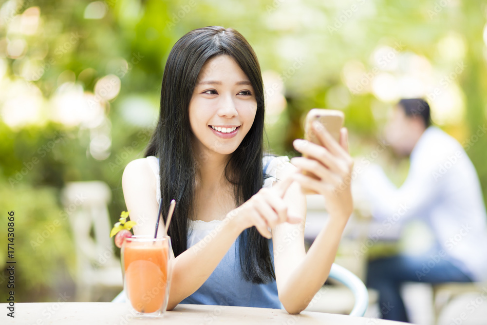 smiling young woman sitting in restaurant watching smart phone