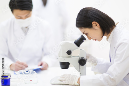 Side view of female scientist using microscope