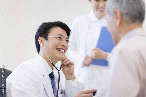 Male doctor examining patient with stethoscope photo