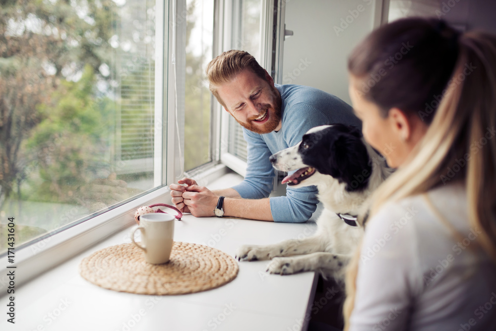 Beautiful couple relaxing at home and loving their dog Beautiful couple relaxing at home and loving their dog