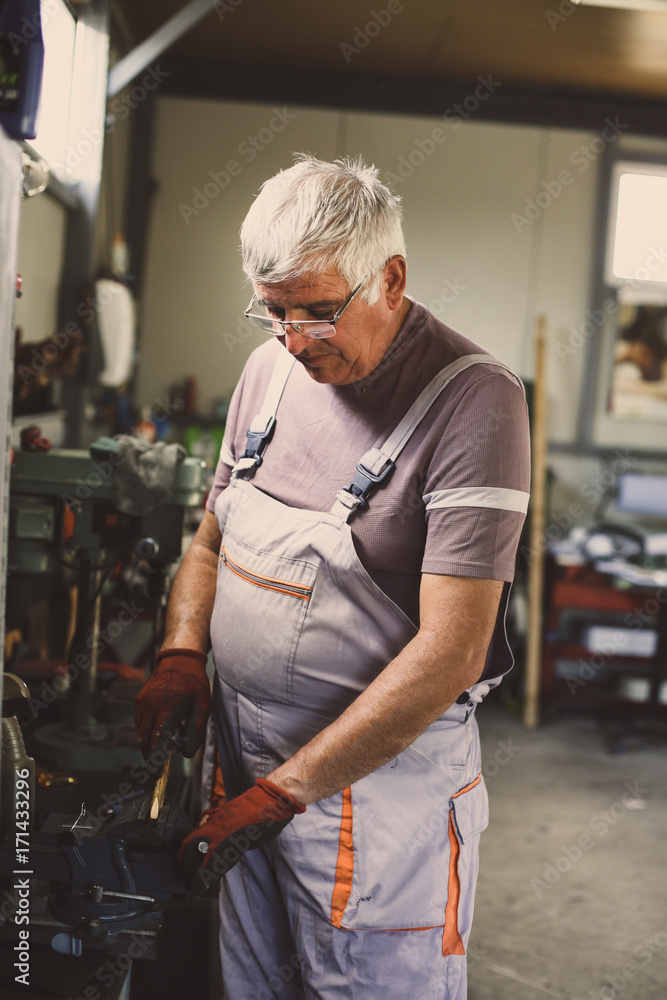 Senior man in workshop. Man cut on machine wood material.