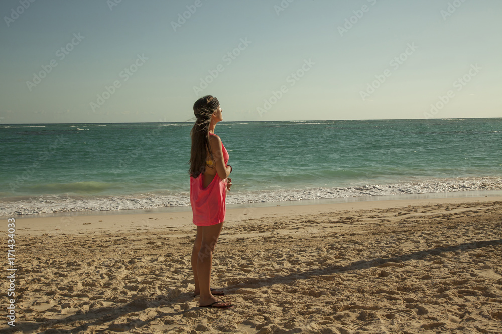 Beautiful woman standing up in the sun. Tropical caribbean beach.