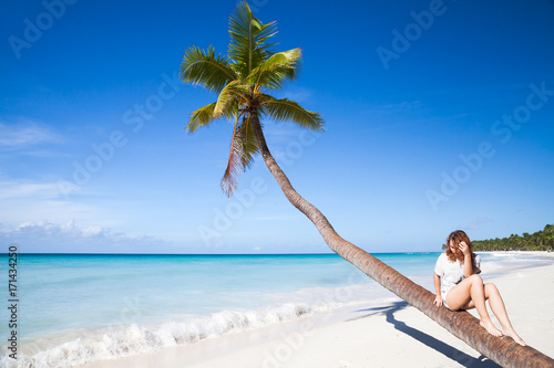 Young girl sitting on a palm tree. Saona island
