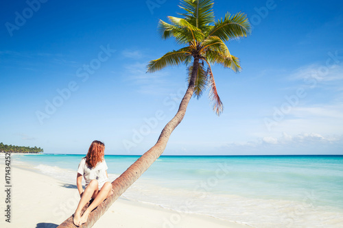 Girl sitting on a palm tree. Saona island beach
