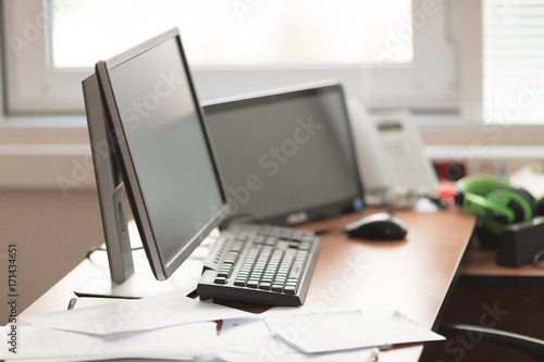 workplace with computer, telephone and papers in  bright office