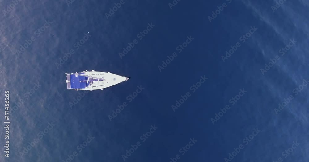 Daytime aerial view of lonely drifting boat in open sea. Sailing vessel in motion Daytime aerial view of lonely drifting boat in open sea. Sailing vessel in motion