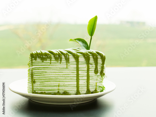 Wallpaper Mural A piece of green tea crepe cake topping with tea leaf and blur of tea plantation background. Torontodigital.ca