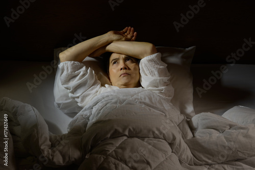 Woman with insomnia lying in bed with open eyes