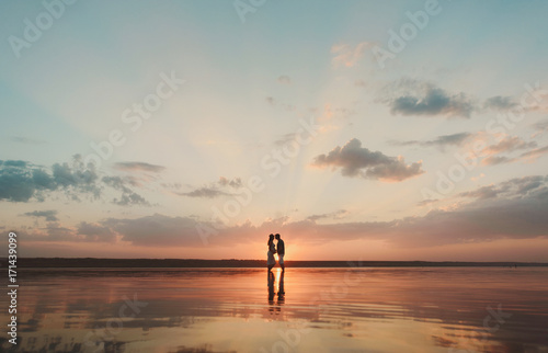 Влюбленная пара стоит в воде на закате солнца