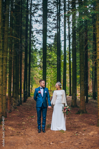 Obraz na płótnie Wedding couple are walking in the forest. Newlyweds embacing in pine park and hug each other w salonie