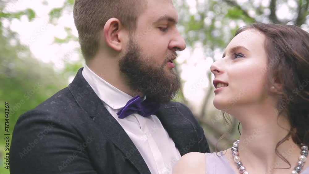 in love a beautiful couple, a girl in a lilac dress and a man with a beard in a jacket walking in the park in love a beautiful couple, a girl in a lilac dress and a man with a beard in a jacket walking in the park