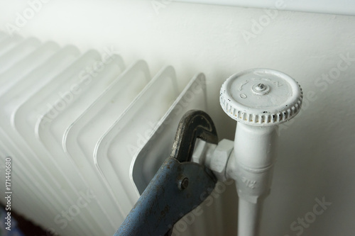 Central heating, white radiator with hand tool repairing