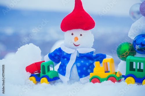 Snowman in red hat and blue coat on snowy background